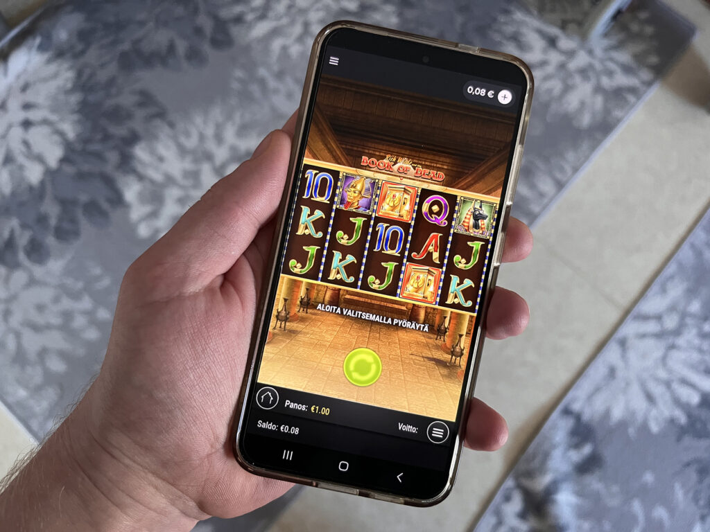 Kuvassa auki puhelin missä avattu Pelikioski Book of Dead -kasinopeli.