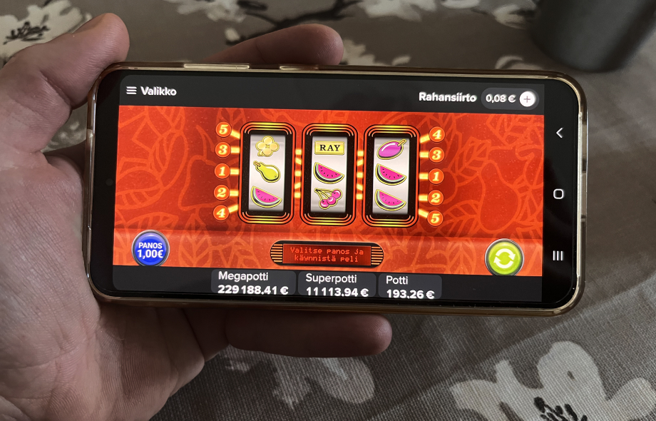 Käsi pitelee älypuhelinta, näytöllä Veikkauksen Tuplapotti-kolikkopeli ja jättipottisummat.