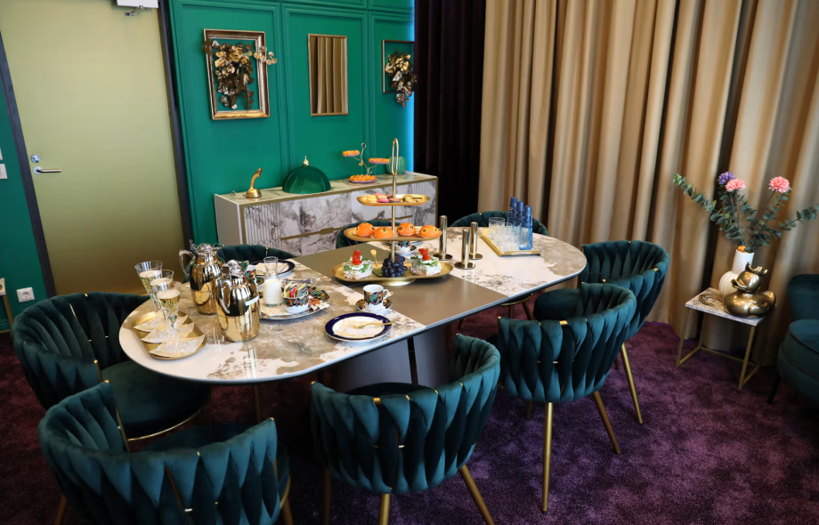 Voittajakabinetin pöytä katettuna juhlavasti: esillä kultaisia kahvipannuja, värikkäitä kuppeja ja makeita sekä suolaisia tarjottavia.