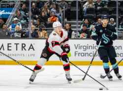 Ottawa Senatorsin Brady Tkachuk kiekkoilee Seattle Krakenia vastaan NHL-ottelussa, taustalla yleisö seuraamassa peliä.