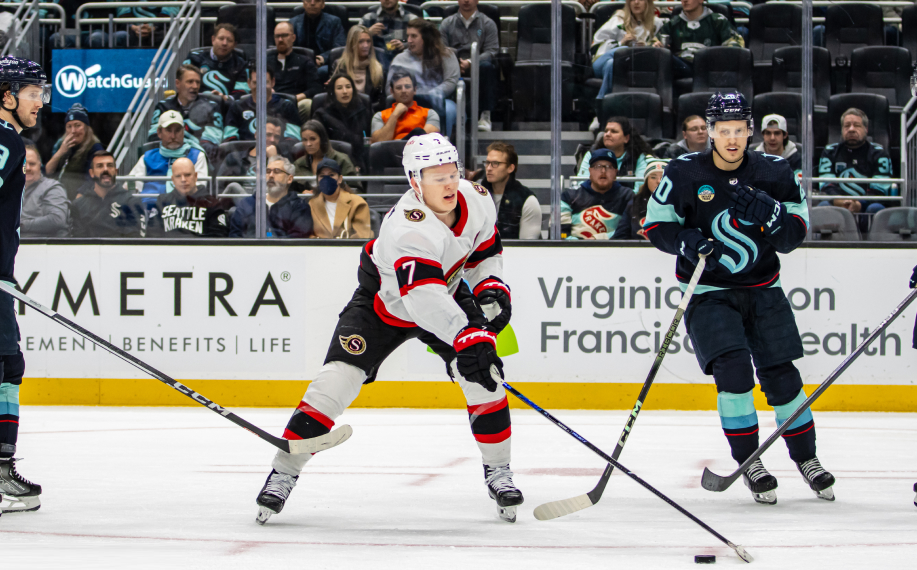 Ottawa Senatorsin Brady Tkachuk kiekkoilee Seattle Krakenia vastaan NHL-ottelussa, taustalla yleisö seuraamassa peliä.