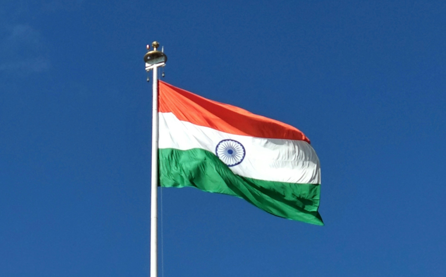 Intian lippu liehumassa sinistä taivasta vasten.