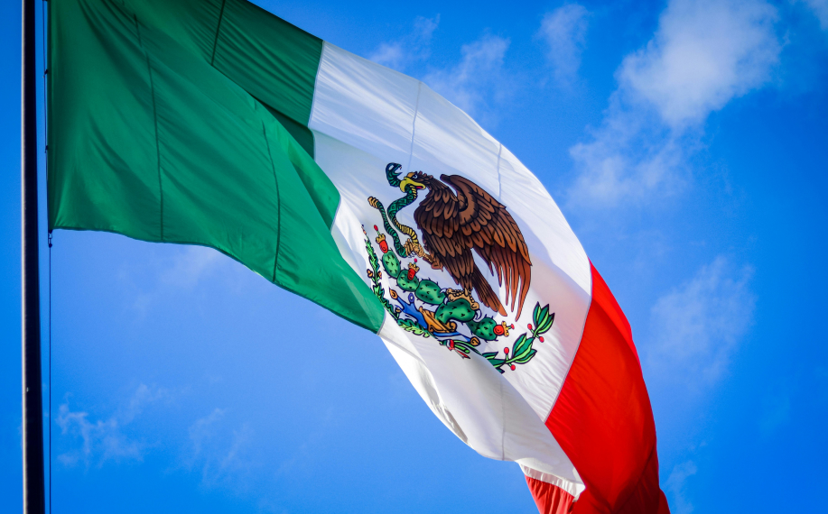 Meksikon lippu liehuu sinistä taivasta vasten.