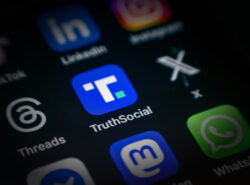 Truth Social appikuvake iPhonen näytöllä. Vieressä Threads ja X.