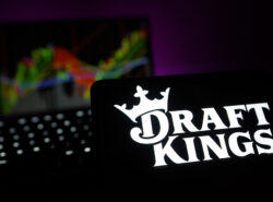 Drafkingsin logo puhelimella, taustalla pörssikurssi.