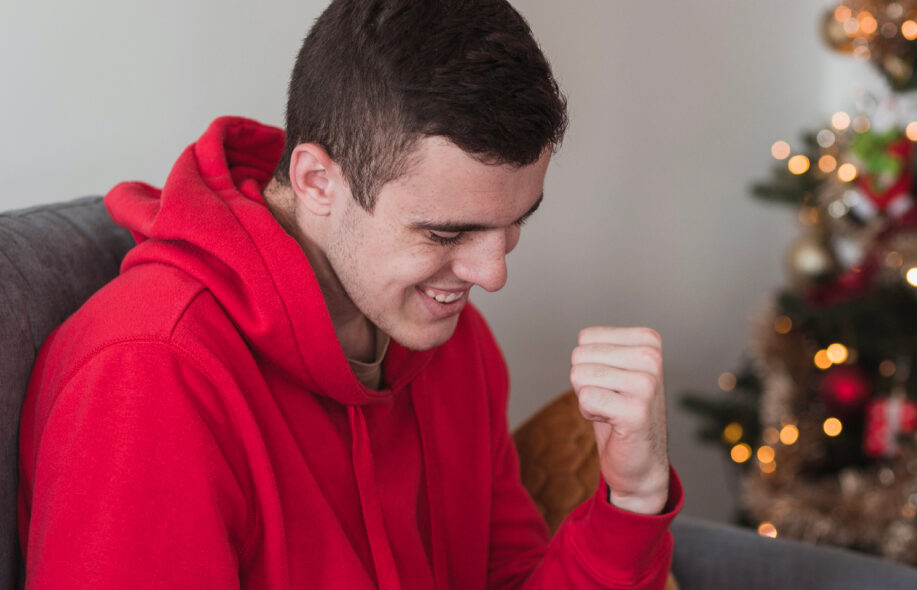 Mies juhlii kasinopeliä, taustalla joulukuusi.