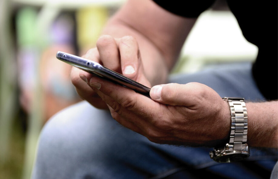 Mies selaa puhelinta.