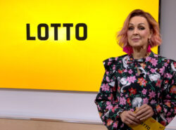 Loton juontaja Lotto-televisioruudun edessä.
