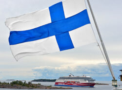 Viking Linen laiva saaristomerellä. Etualalla liehuu Suomen lippu.