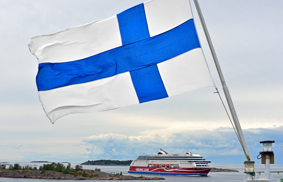 Viking Linen laiva saaristomerellä. Etualalla liehuu Suomen lippu.