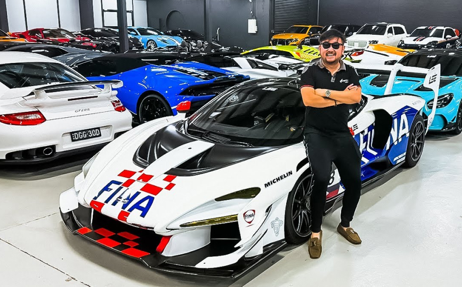 Mies poseeraa kymmenien superautojen kanssa.