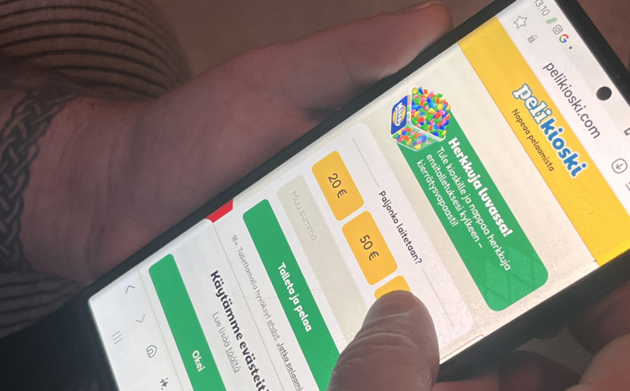 Pelikioski nettikasino auki pelaajan kädessä. Kuvasta voi päätellä että kyseessä on kasino ilman rekisteröitymistä koska pelaaja on evästeilmoituksen perusteella siellä ensimmäistä kertaa ja edessä on suoraan talletusnäkymä ilman rekisteröitymistä.