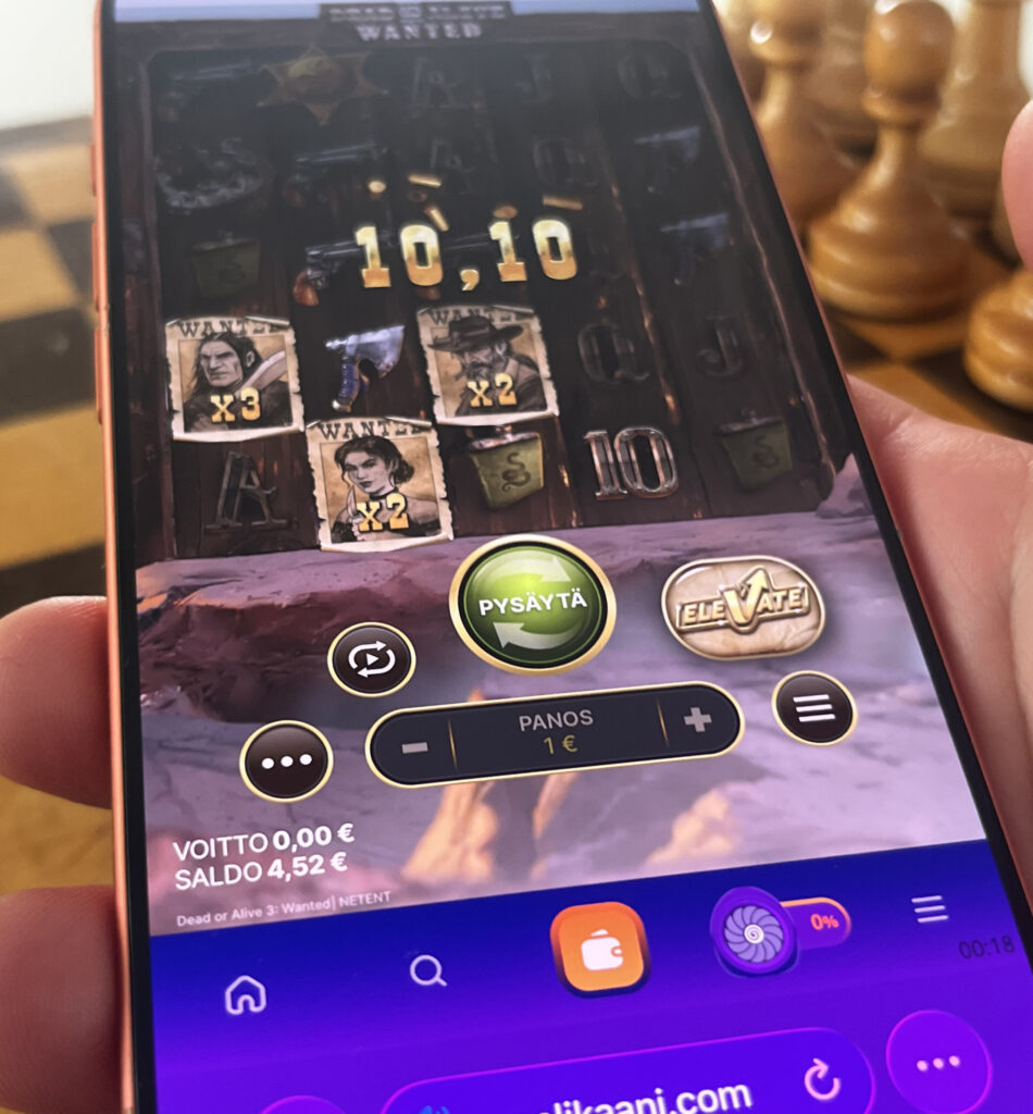Puhelimen näytöllä auki Pelikaani nettikasino, missä Dead or Alive 3 Wanted -kolikkopeli, jossa näkyvät wanted-symbolit kertoimineen, panos 1 euro sekä pelin käyttöliittymä länkkäriteemassa.