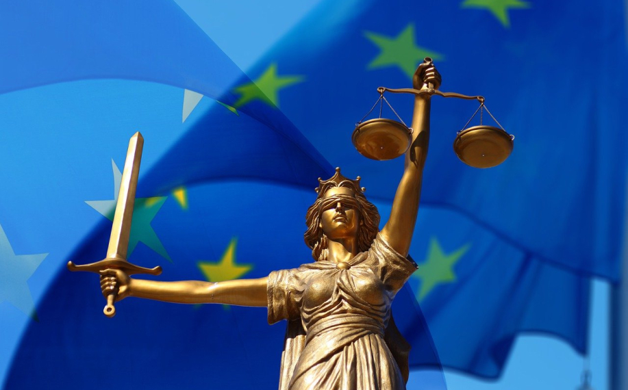 Oikeutta kuvaava naispatsas EU lipun edessä. Hieman abstraktin näköinen.