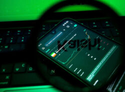 Kalshi auki puhelimessa. Etualalla abstraktilta näyttävä suurennuslasi.