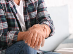 Vanhempi mies pitää toisesta kädestään kiinni mikä näyttää vapisevan.