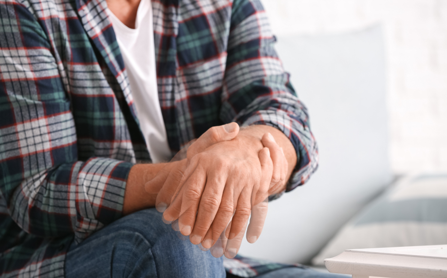 Vanhempi mies pitää toisesta kädestään kiinni mikä näyttää vapisevan.