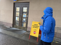 Veikkaus Lotto-mainos Helsingin Rautatiaseman ulkopuolella märässä ja synkässä kelissä.