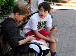 Kaksi nuorta poikaa keskustelevat ja käyttävät puhelimia