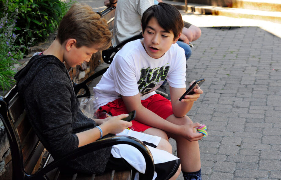 Kaksi nuorta poikaa keskustelevat ja käyttävät puhelimia