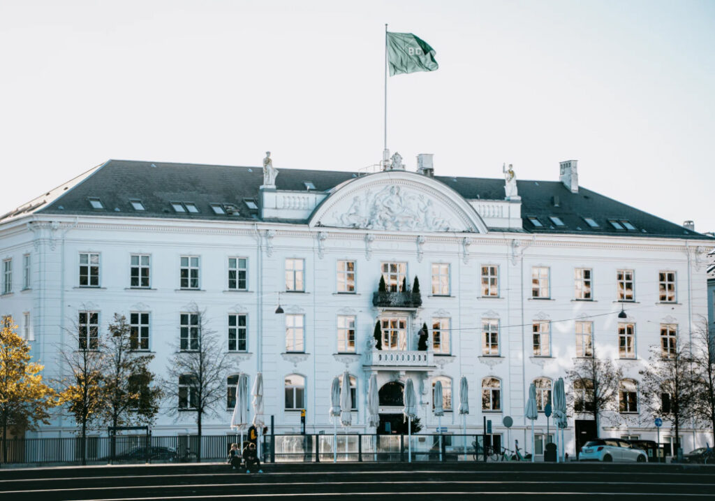 Hulppea vanhanaikainen toimistorakennus minkä katolla liehuu "BC (Better Collective)" lippu.