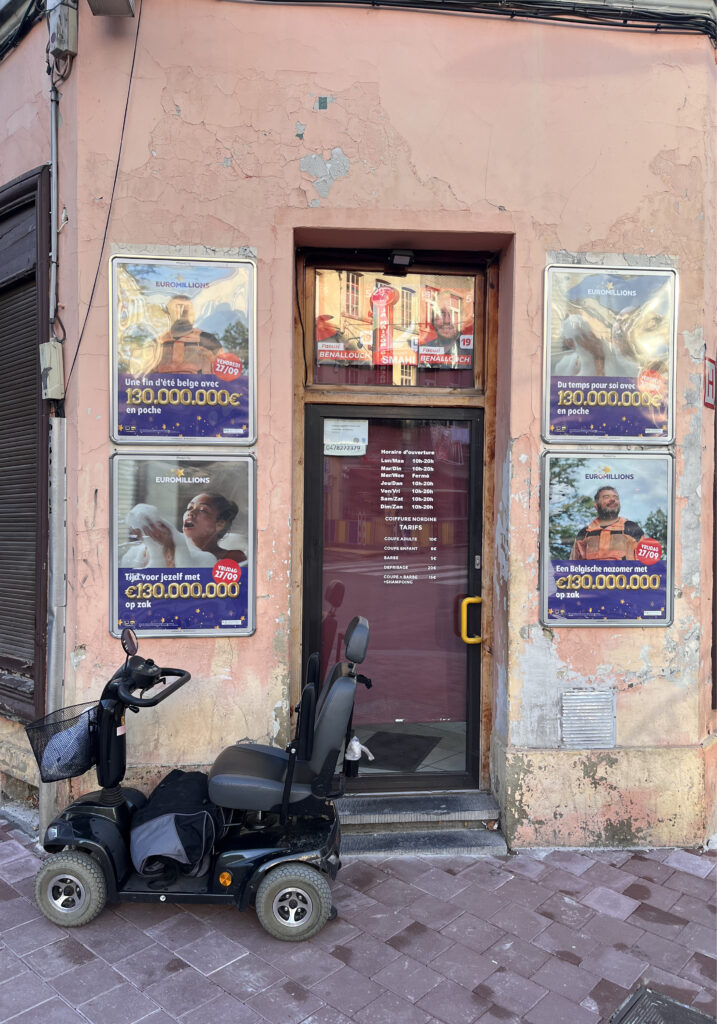 Euromillions mainoksia lottokonttorin ovella. Edessä liikuntarajoitteisen apuväline.