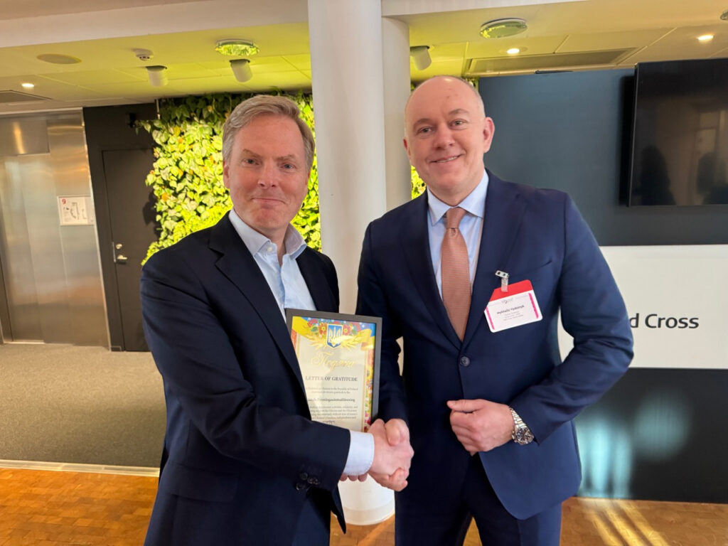 Christer Fahlstedt ja Mykhailo Vidoinyk kättelevät. Fahlstedtillä kädessään kiitoskirje Ukrainalta