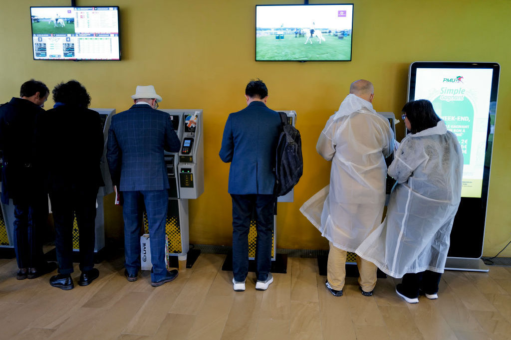 Ravivedonlyöjiä käyttämässä vedonlyöntiautomaatteja Pariisin Longchampin raviradalla Ranskassa.