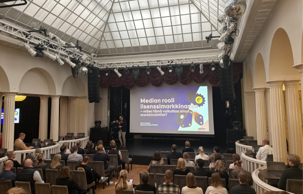 Karri Ahonen pitää esitystä median roolista lisenssimarkkinassa puolitäydessä seminaarisalissa Helsingissä.