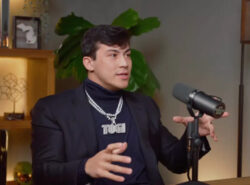 Togi podcastissa. Isokokoinen nuori mies. Kaulassa bling-koru missä lukee "Togi".