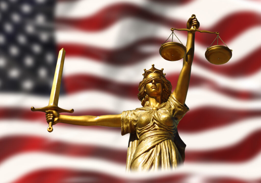 Oikeutta kuvaava patsas yhdysvaltojen lipun edessä.