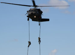 Kaksi sotilasta laskeutuu köyden varassa helikopterista.