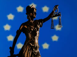 Oikeuden jumalatar ja Euroopan unionin lippu taustalla.