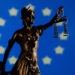 Oikeuden jumalatar ja Euroopan unionin lippu taustalla.