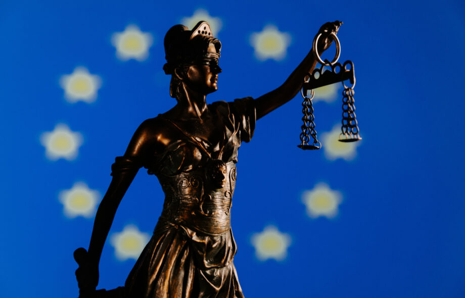 Oikeuden jumalatar ja Euroopan unionin lippu taustalla.