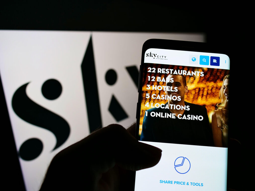 Älypuhelin, jossa näkyy SkyCity Entertainment Groupin verkkosivu. Taustalla yhtiön logo.