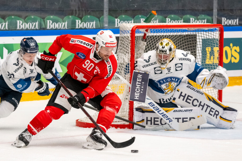 Sveitsin Roman Josi kiekkoilee Suomen maalilla. Suomen pelaajilla paidoissaan Veikkauksen logot.
