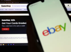 Ebayn logo puhelimessa, taustalla Gamestop-verkkosivu vihjaa että heidän kauttaan voi arvioida keräilykorttien kunnon ja myydä ne.
