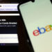 Ebayn logo puhelimessa, taustalla Gamestop-verkkosivu vihjaa että heidän kauttaan voi arvioida keräilykorttien kunnon ja myydä ne.