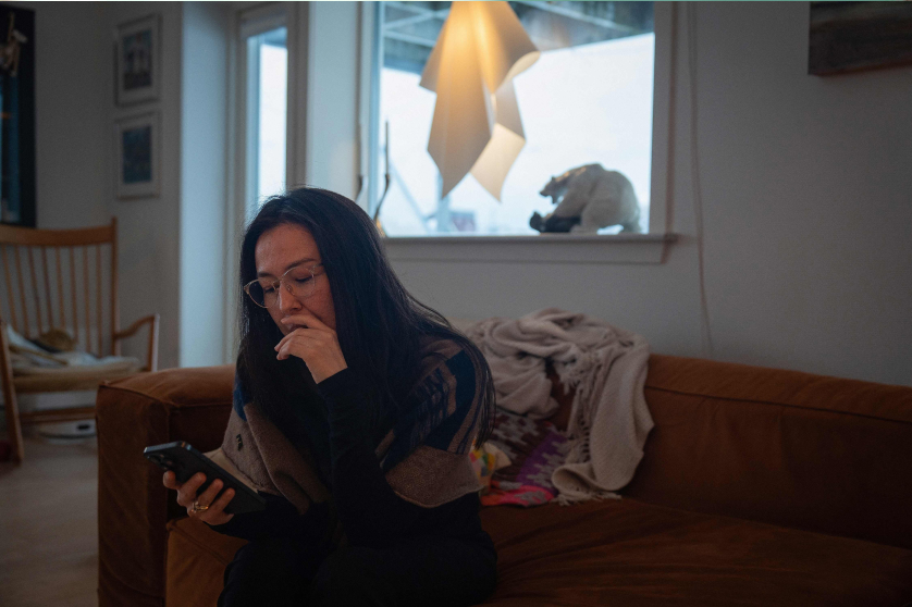 40-vuotias nainen katselee puhelintaan kotonaan Nuukissa, Grönlannissa, 16. tammikuuta 2026.