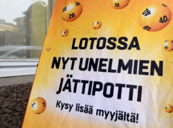 Kadulla ajattomalta näyttävä kyltti kertoo lotossa olevan unelmien jättipotti. Kehottaa kysymään lisää myyjältä.