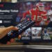 Television ruudulla näkyy Netflixin urheilusisältöä ja NFL-aiheinen ohjelmavalikko, kun katsoja pitää kaukosäädintä kädessään.