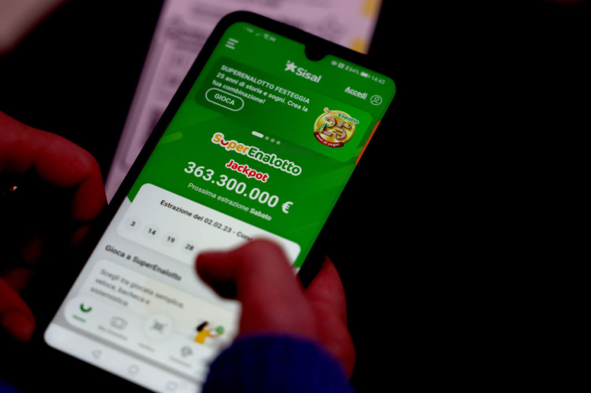 Käsi pitelee älypuhelinta, jonka näytöllä on auki Sisalin nettikasino. Vihreällä etusivulla näkyy SuperEnalotton 363 300 000 euron jackpot ja seuraavan arvonnan ajankohta. Yläreunassa on SuperEnalotton 25-vuotisjuhlabanneri.