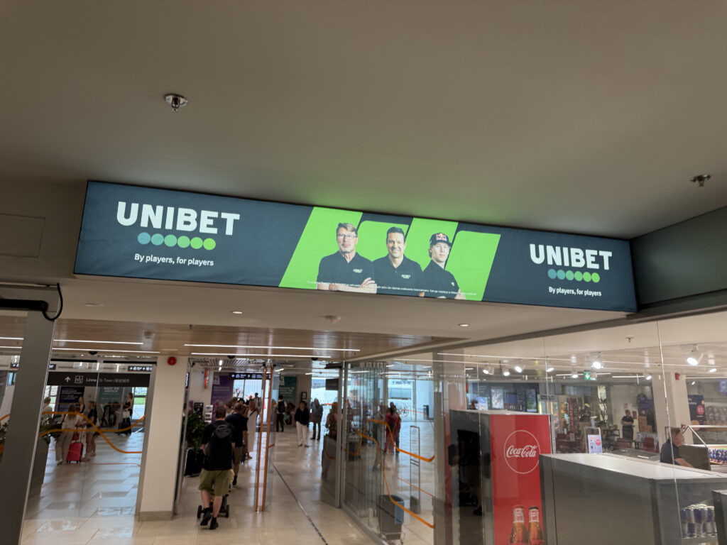Tallinann satamassa sisääntuloaulassa Unibet kyltissä näkyy Mika Häkkinen, Jari Litmanen ja Kalle Rovanperä.