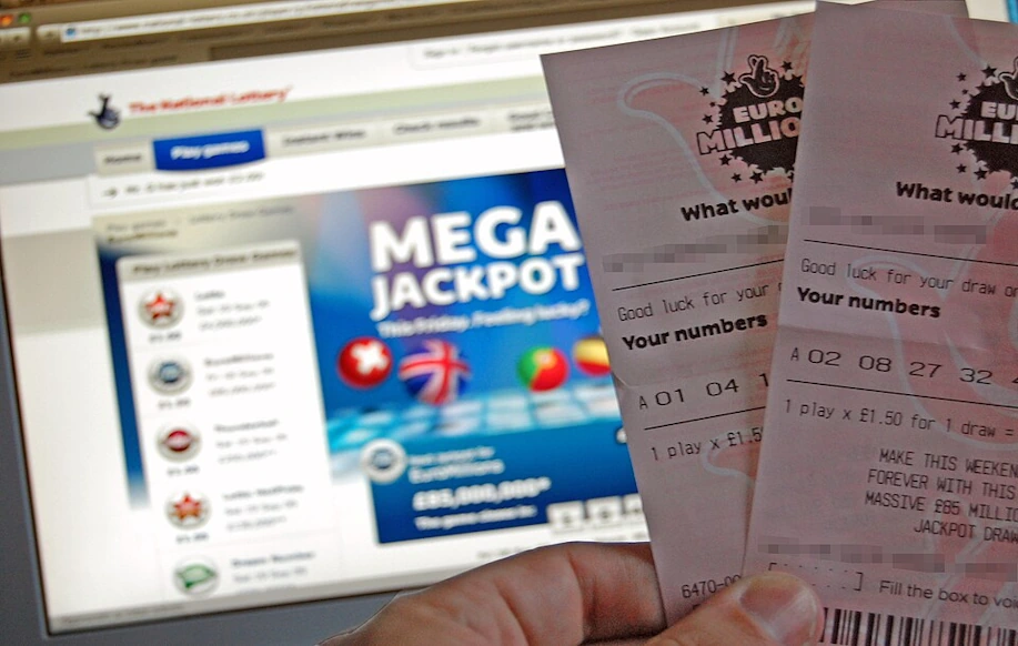 EuroMillions-lottokuponkeja henkilön kädessä. Taustalla National lottery sivu auki tietokoneen näytöllä. Näytöllä maininta Mega Jackpotista.