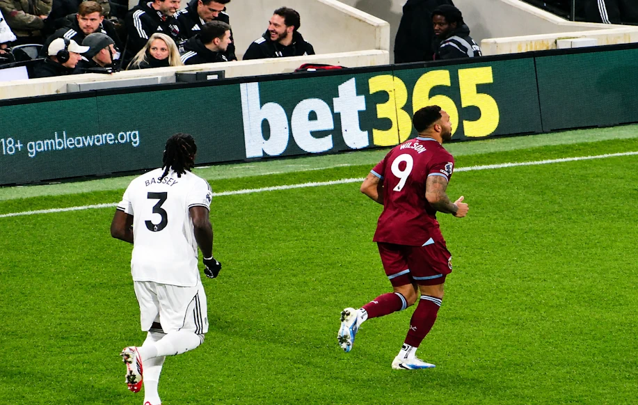 Fulhamin Calvin Bassey ja West Hamin Calum Wilson juoksevat kentällä bet365:n LED-mainoksen edessä.
