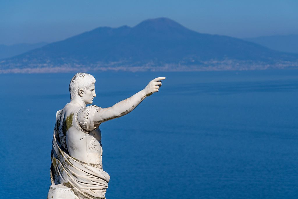 Augustusta esittävä patsas Caprissa korkealla paikalla. Taustalla Napolinlahti ja Vesuvius-tulivuori.
