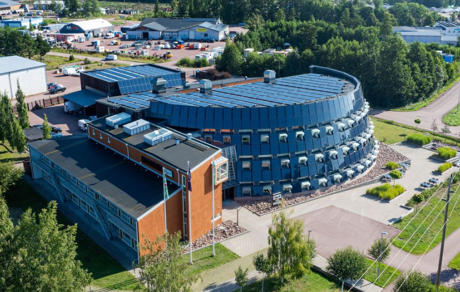 Pafin toimistorakennus/rakennukset ilmakuvassa Ahvenanmaalla. Futuristinen muoto. Taustalla luonto ja teollisuusaluemaisemaa.