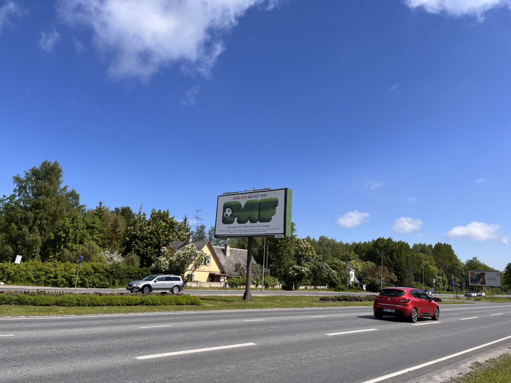 Paf katumainos liikenneväylän vieressä kuvattuna kesällä 2025. Paf logo jalkapallon viheriö ja "P" kirjaimen aukko jalkapallona. Karu valtatie.