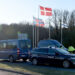 Tanskassa poliisiautot ja poliisit estävät rajan. Taustalla Pohjoismaiden lippuja rajan yhteydessä. Kuvattu Tanskan puolelta.